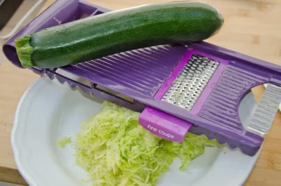 Râper les courgettes pour faire la pâte à gâteaux